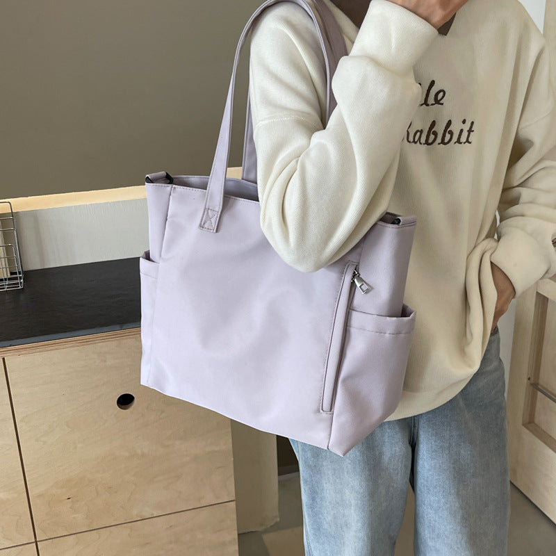 világosszürke nagyméretű textil tote táska modellen közelről vállon hordva