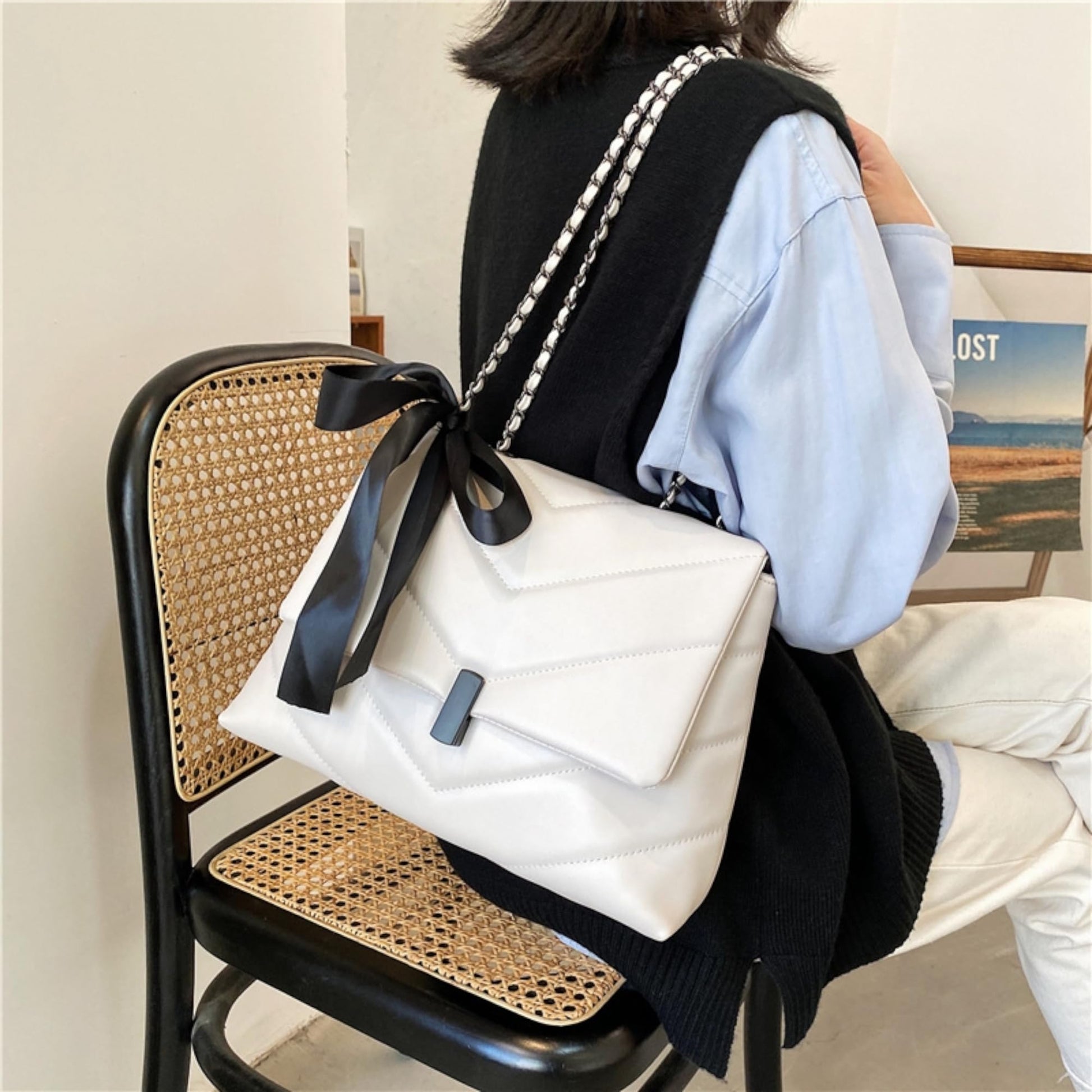 fehér steppelt női crossbody táska ülő modellen hordva láncpánttal és fekete masnival