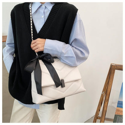 fehér steppelt női crossbody táska modellen elöl hordva fekete masnival