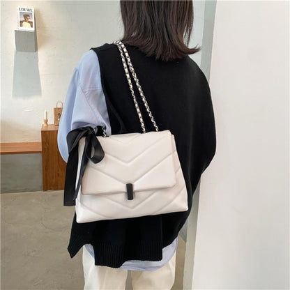 fehér steppelt női crossbody táska modellen hátulról hordva láncpánttal