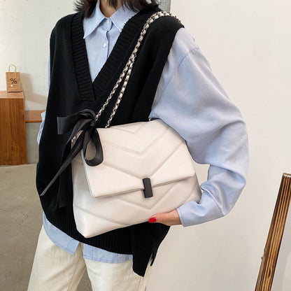 fehér steppelt női crossbody táska modellen vállon hordva fekete masnival